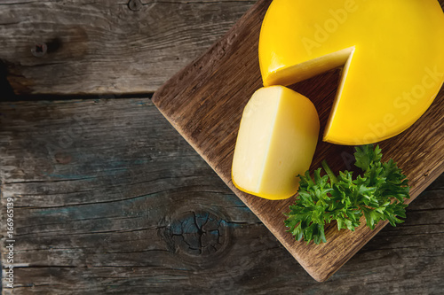 Round gouda cheese with parsley. Dark background.