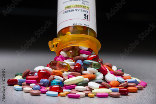 A prescription pill bottle spilling out an assortment of pills