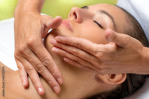 Hands applying neck cream on woman.