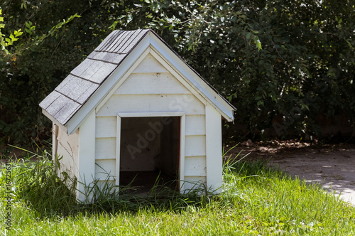 White wooden doghouse on a house backyard