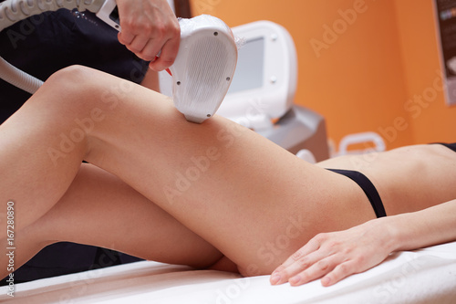 Beautician Removing Hair Of Young Woman's legs
