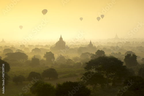 Hot air balloons fly over the pagoda ancient city field on silhouette sunrise scene at Bagan Myanmar.