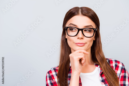 Portrait of sceptic young freelancer brown haired lady, she is in glasses, casual wear, on pure light background. So pensive and sexy