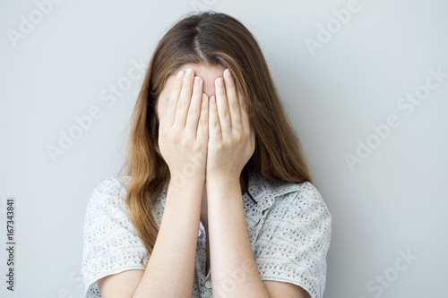 Shy girl covering up her face with her hands