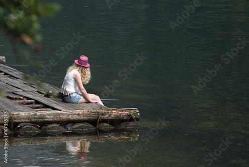 Girl sitting on dock on lake