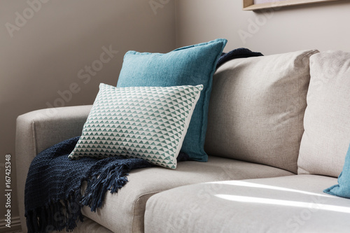 Close up of a fabric sofa with styled cushions and throw