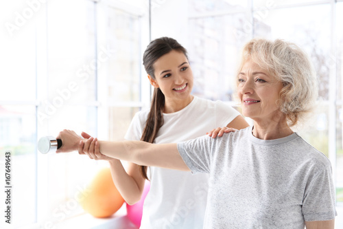 Physiotherapist working with elderly patient in modern clinic