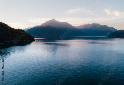 Aerial shot of kayaker on lake with mountains while sunset