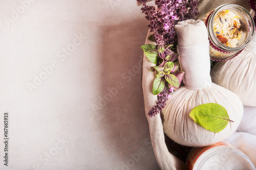 Massage setting with herbal compress balls ,fresh herbs and flowers and bathroom salts on light background,top view. Healthy Lifestyle or Spa and wellness concept