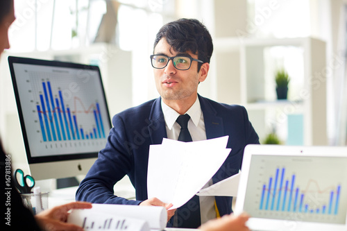 Young economist talking to colleague and explaining financial papers