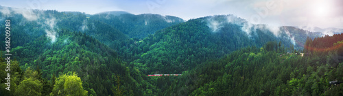 Panorama of small train in Black Forest covered in soft clouds