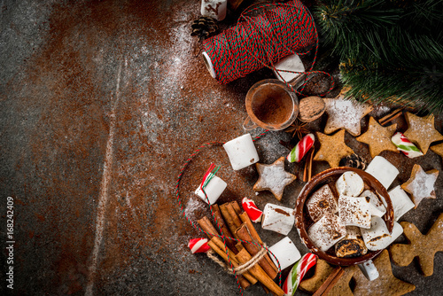 New Year, Christmas treats, sweets. Cup of hot chocolate with fried marshmallow, ginger star cookies, gingerbread men, striped candy, spices cinnamon anise, cocoa, powdered sugar. Copy space top view