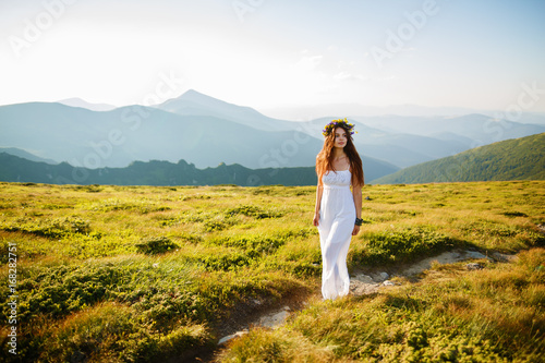 Beauty woman portrait with wreath from flowers on head, Beautiful young long hair woman posing in high mountain scenery. Rocky mountain