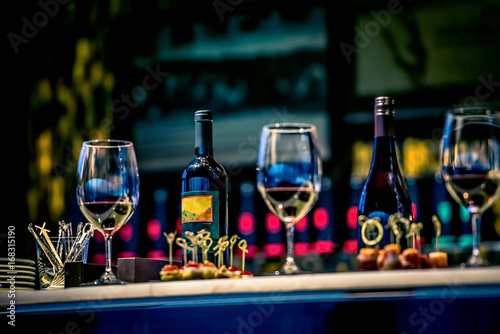 Snacks, glasses of wine and bottles on bartender counter in restaurant