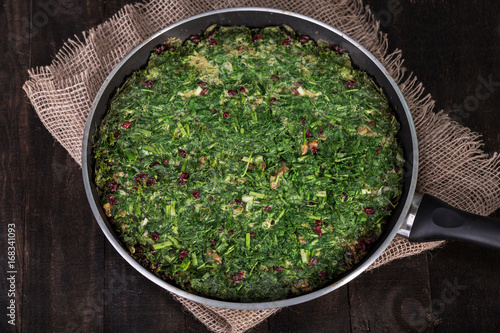 Persian Mixed herbs frittata with barberry and walnut in pan (Kuku and Zereshk)
