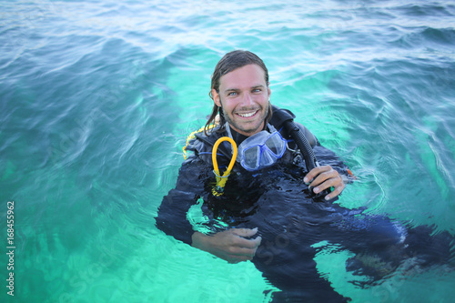 Handsome guy in the sea, carrying scuba diving equipment