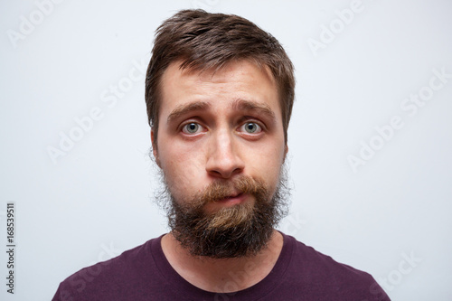 Young bearded man uncertain what to do with his messy beard and moustache