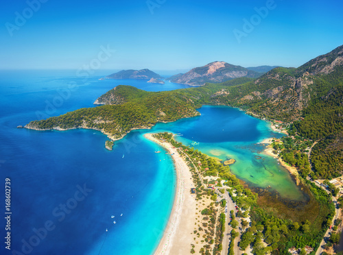 Amazing aerial view of Blue Lagoon in Oludeniz, Turkey. Summer landscape with mountains, green forest, azure water, sandy beach and blue sky in bright sunny day. Travel background. Top view. Nature