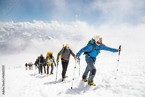 A group of mountaineers climbs to the top of a snow-capped mountain