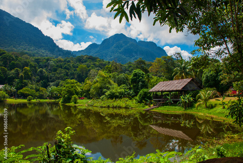 Traditional wooden house near the lake and mountain in the background. Kuching to Sarawak Culture village. Borneo, Malaysia