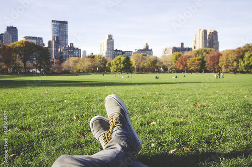 Persona relajándose en el parque de Central Park en New York con árboles y edificios de fondo