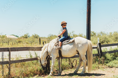 Happy little boy enjoying summer vacation in Camargue, France. Child visiting horse ranch