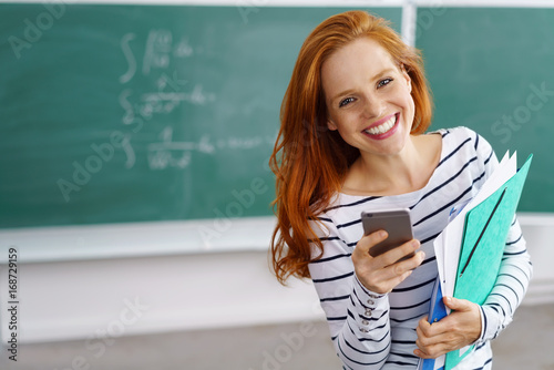 lachende lehrerin mit handy in der schule