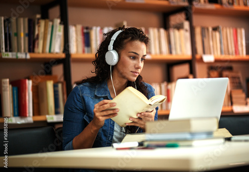 Young female student study in the school library.She using laptop and learning online.