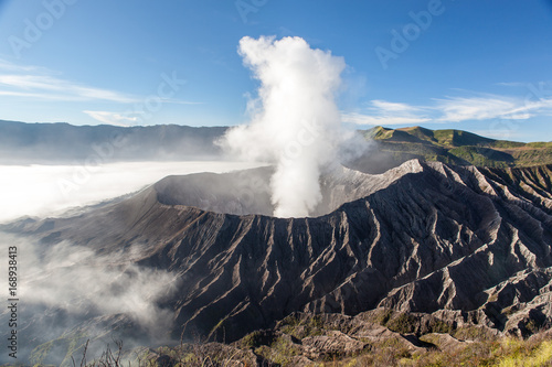 Bromo volcano crater at sunrise in morning mist from mt. Batok summit.