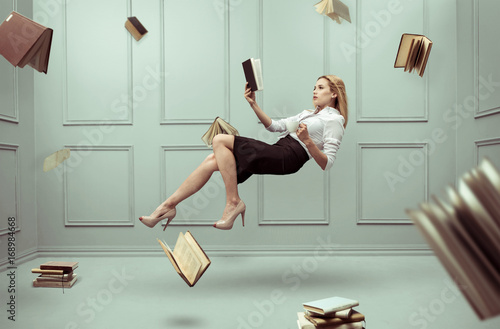 A relaxed woman levitates in a room full of flying books