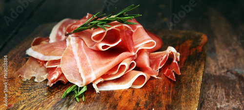 Italian prosciutto crudo or jamon with rosemary. Raw ham.