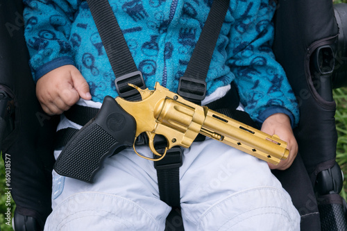 Sleeping baby with a gun in his hands