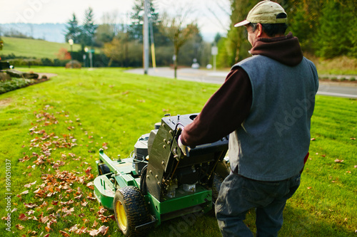 man mowing a lawn in the morning with leaves