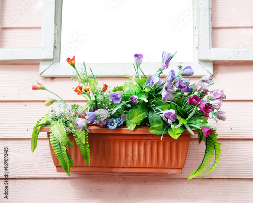 jardiniere on window with pink wood background and plastic flower