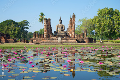Ruins of ancient Buddhist temple Wat Chana Songkram on the shore of a lake with pink lilies. Sukhothai, Thailand