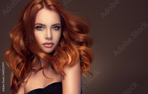 Piękna modelka z długimi rudymi kręconymi włosami. Czerwona głowa. Produkty do pielęgnacji, farbowanie włosów.