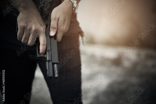 Robber holding gun for ready to murder steal moneys at abandoned building. Selective focus. criminality and social issues concept. Dark and low key tone tone pinterest and instragram like process.
