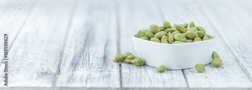 Portion of Wasabi coated Peanuts on wooden background (selective focus)