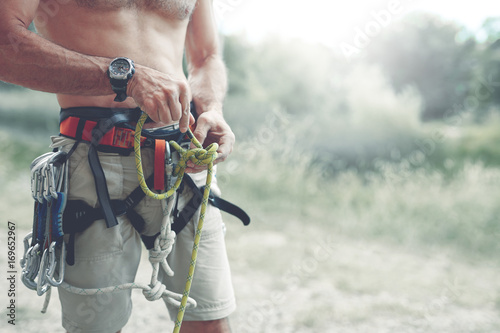 A man climber Knots a knot on a climbing harness. hands in chalk close up