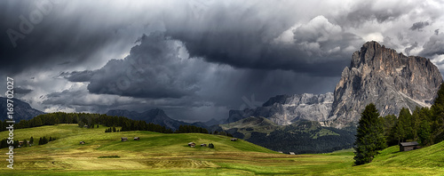 Storm over the mountains Dolomiti in the summer season with meadow in foreground 