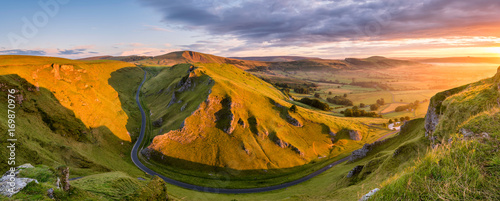 Wide panoramic view of Winnats Pass in the Peak District with vibrant morning light.