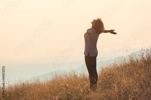 Young woman standing on mountain and having fun on grass field