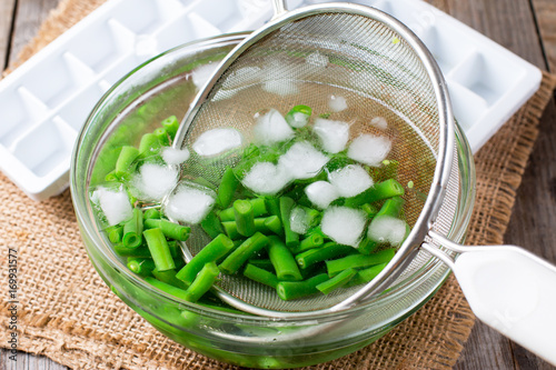 Boiled vegetables, green beans in ice water after blanching