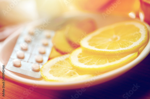 lemon slices, pills and ginger on plate