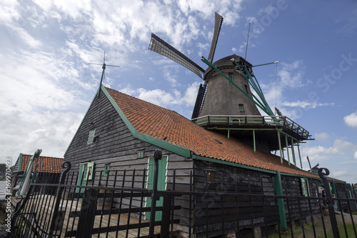 Windmill on tile roof of building and sky as background. Typical windmill and building in Zaanse Schans, Netherlands