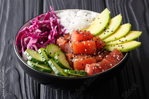 Organic food: tuna poke bowl with rice, fresh cucumbers, red cabbage and avocado close-up. horizontal