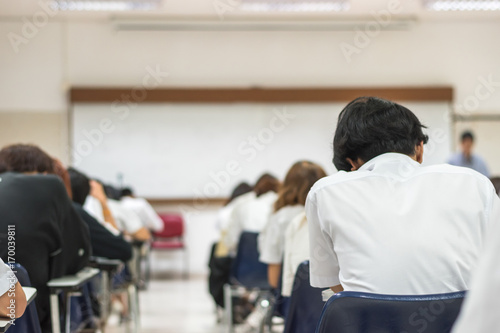 Education blur background back view university students writing answer doing exam in school classroom