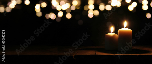 Burning candles over black background with bokeh glitter lights