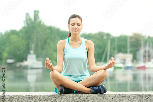 Morning of young woman practicing yoga outdoors