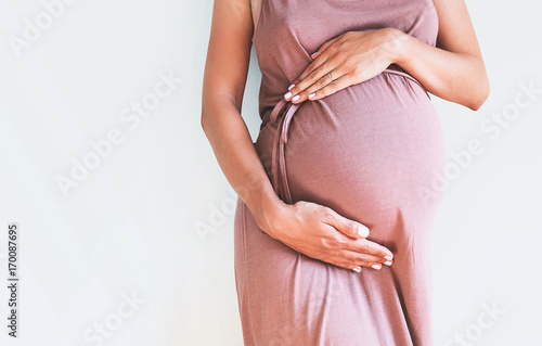 Pregnant woman holds hands on belly. Close-up